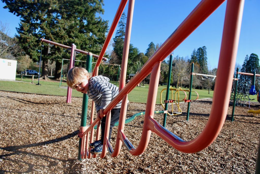 Nathan from Backyard Travel families tests out the climbing frame at the Ashburton Domain Playground