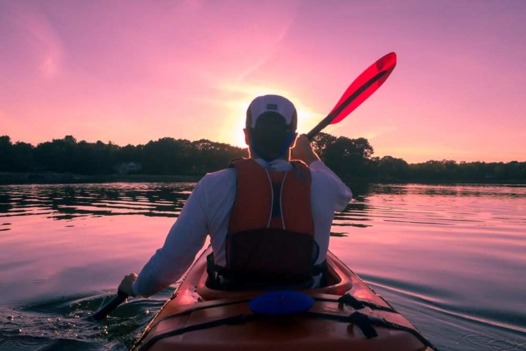 Kayaker at sunset. To find out the cost of these types of activities, check out our Cost of Travel in New Zealand article I Backyard Travel Family