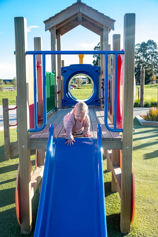 1 year old Emilia from Backyard Travel Family attempts the slide at Foster Park Playground, Rolleston, Christchurch, New Zealand
