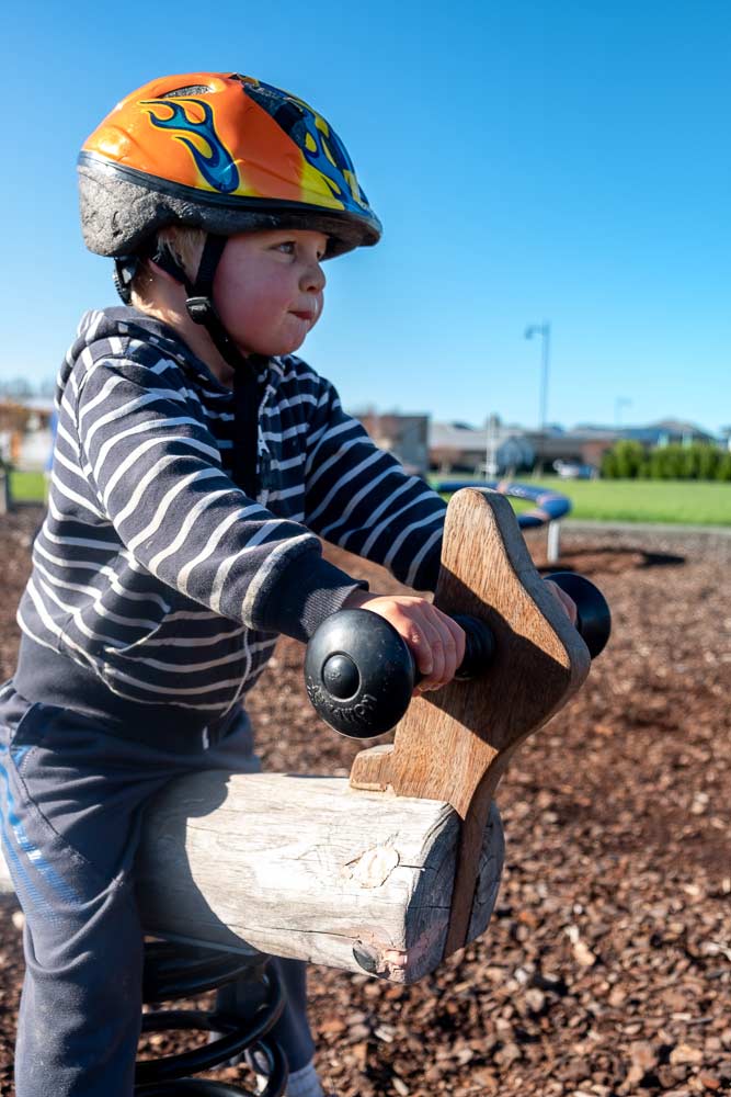 Kipton from Backyard Travel Family rides the rocker at Neil Graham Park Playground, Chch, New Zealand