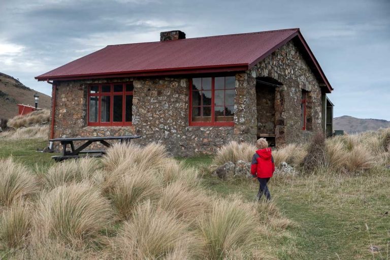 Kipton from Backyard Travel Family checks out the historic Packhorse Hut, looking over Banks Peninsula, Christchurch, NZ
