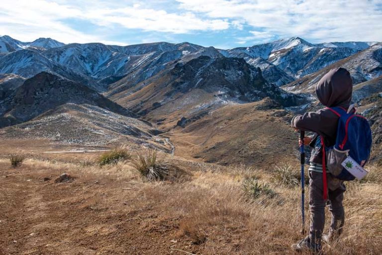 Nathan looking down towards Woolshed Creek Hut in the distance, just 20 minutes from the end of the best overnight hike for kids in Mid Canterbury, NZ