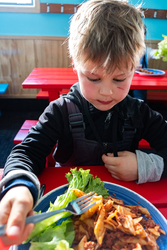 Nathan from Backyard Travel Family tucks into the delicious pasta meal with salad and fruit at his Kea Club Ski School Programme at Mt Hutt