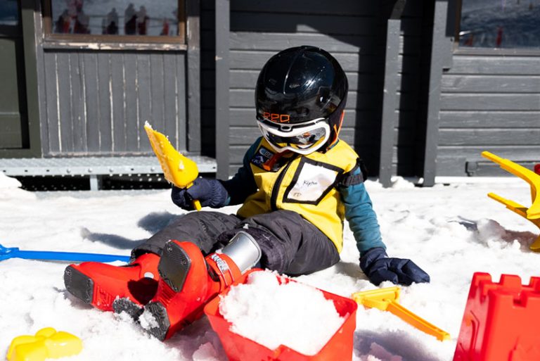 Kipton from Backyard Travel Family makes ice castles with sandcastle buckets in the snow, outside Skiwiland Preschool on Mt Hutt Ski Field