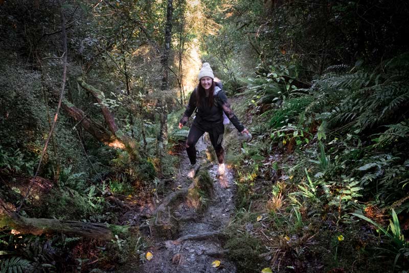 Jen from Backyard Travel Family negotiates the mud and tree roots while climbing uphill in the Awa Awa Rata Reserve