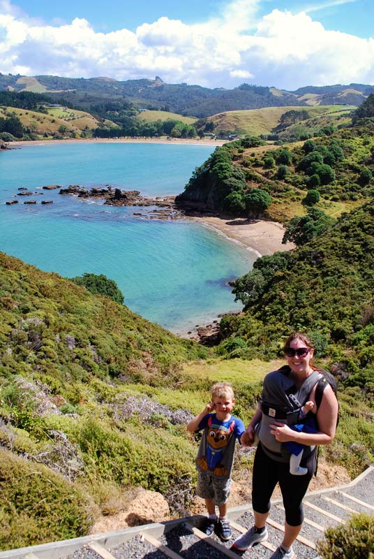 Jen and Nathan walk up the stairs, overlook Mahinepua Bay on the Mahinepua Peninsula Track