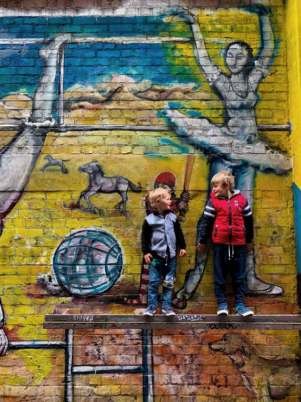 Nathan and Kipton from Backyard Travel Family become part of the street art on Opera Lane in Wellington