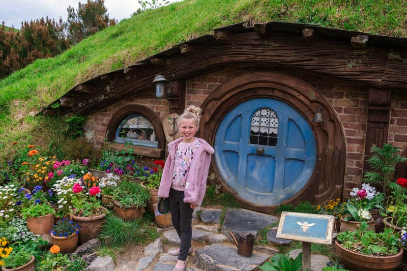 emilia stands outside a hobbit hole at hobbiton, matamata