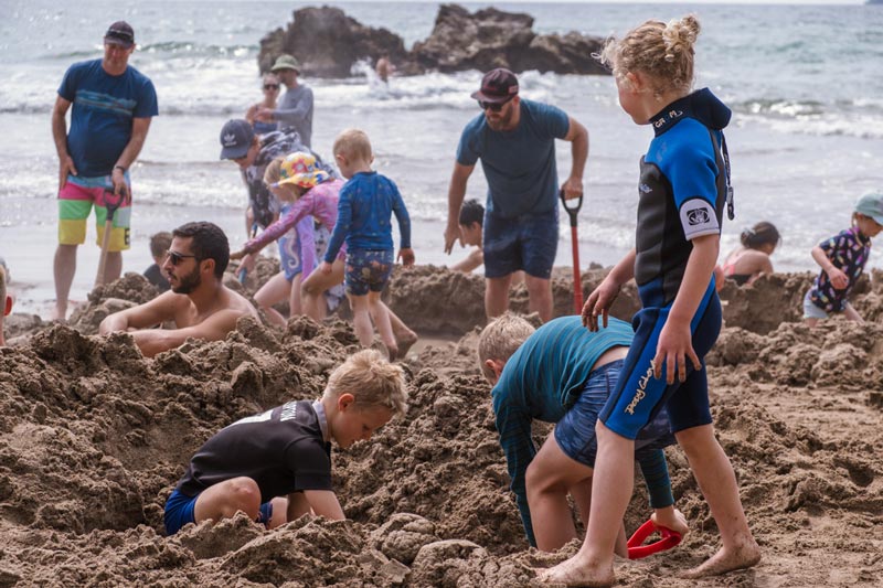 kids dig in the sound at the famous hot water beach in new zealand