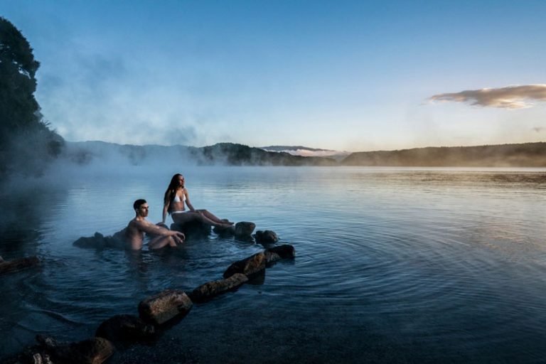 Couple swims in geothermal steamy waters in a lake in Rotorua