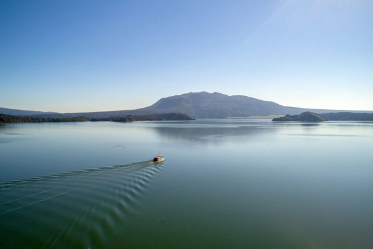 Amazing views of a boat in the lake on a clear blue day in Waimangu Valley Rotorua