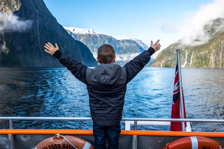 Nathan from Backyard Travel Family puts out his arms in excitement to be on the Go Orange Milford Sound Cruise