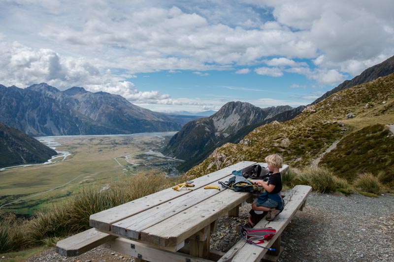 Kipton sitting at the large wooden picnic table at the top of the Sealy Tarns Track, Mt Cook National Park, New Zealand