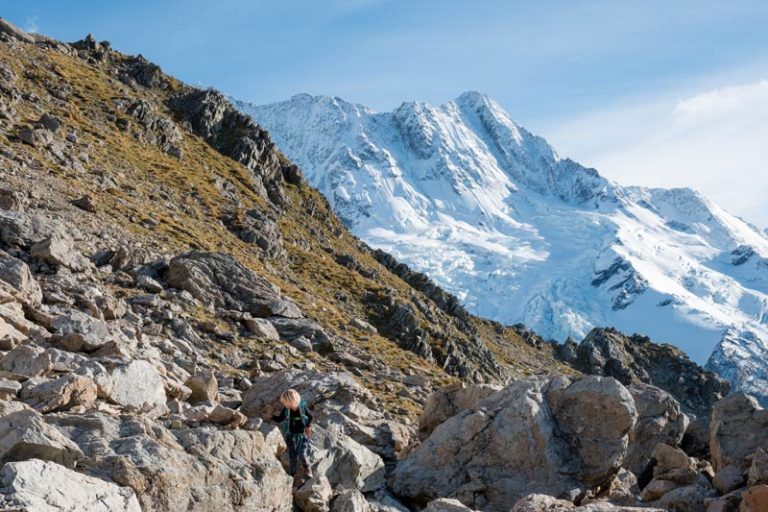 Kipton from Backyard Travel Family climbs boulders on route to Mueller Hut, with the snowy Southern Alps in the background.