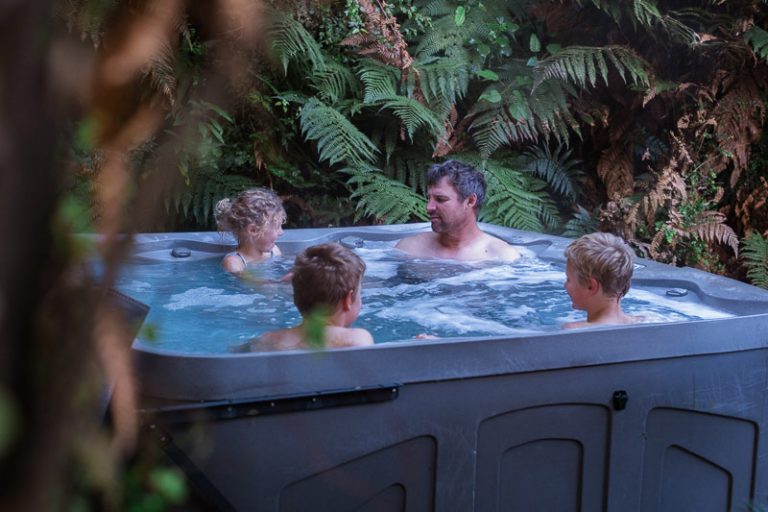 Family sits in the spa pool at the Neinei house at Franz Josef Rainforest Treat