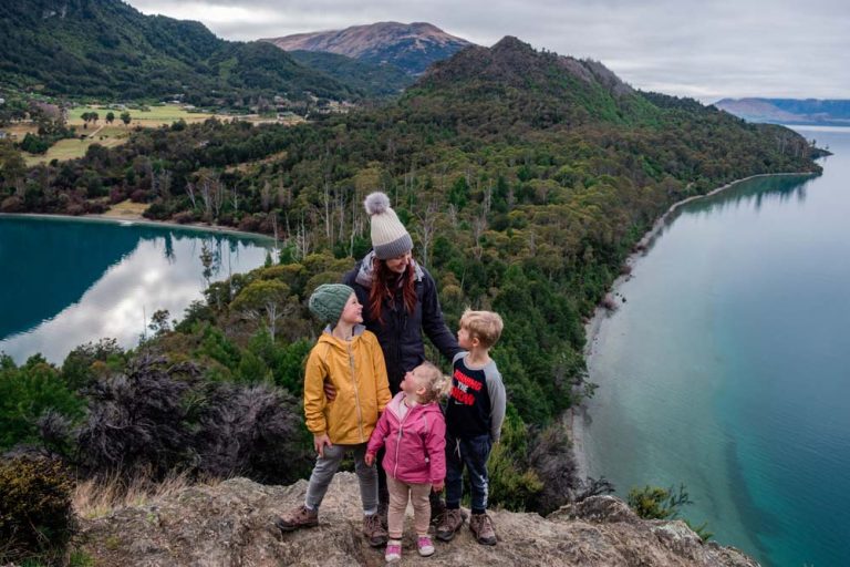 Backyard Travel Family delight in reaching the top of Picnic Point, Bobs Cove. With incredibles blue green waters of Lake Wakatipu in behind them.