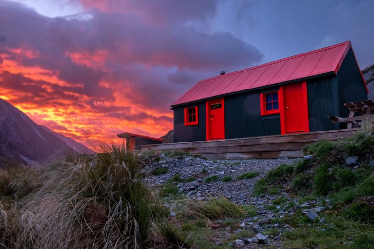 Fiery red and yellow sunrise behind the Hooker Hut New Zealand
