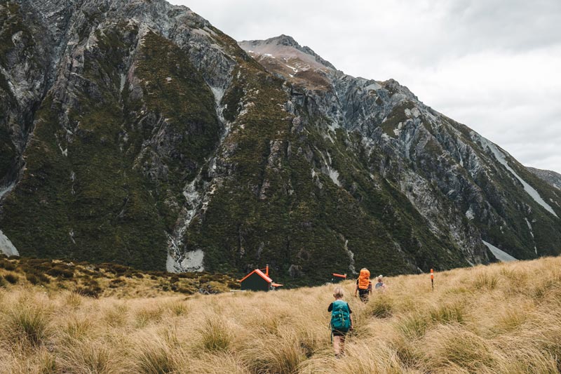 Following the orange markers and finally seeing the tip of the Hooker Hut, with beautiful mountains in the background