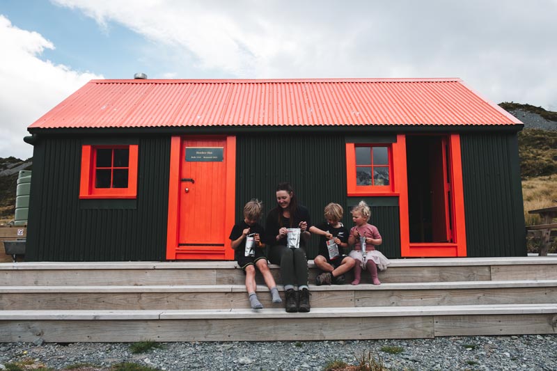 Backyard Travel Family eat Radix meals in front of the Hooker Hut, the best family friendly hut in New Zealand
