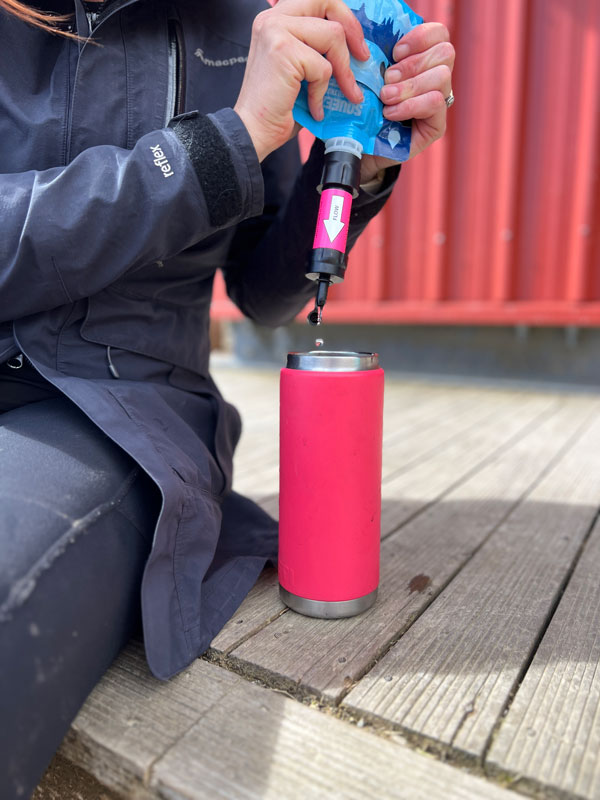 the sawyer mini water filter is being used to filter water into a yeti water bottle. Its a great piece of tramping gear for families