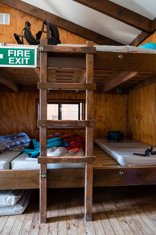 A double platform wooden bunk bed sleeping four on top and four on the bottom in the sleeping room at Luxmore Hut
