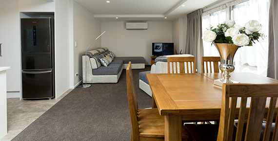 Large wooden table and couches in the spacious family suite at 239 on Lincoln motel in Christchurch