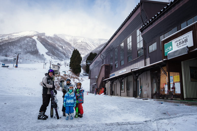 family stand in front of the gondola station at ski resort in Hakuba