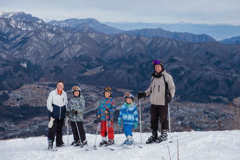 family of 5 take a photo of skiing in hakuba up the mountain at Hakuba Happo ski resort