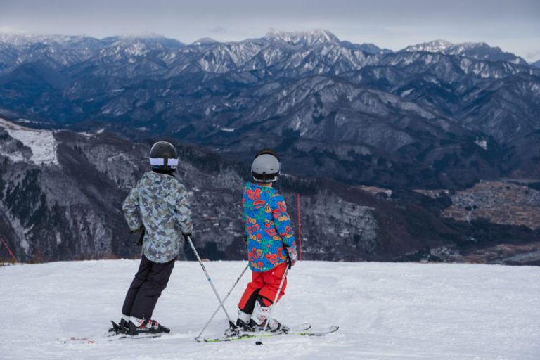 two kids skiing in hakuba japan look over mountains ahead