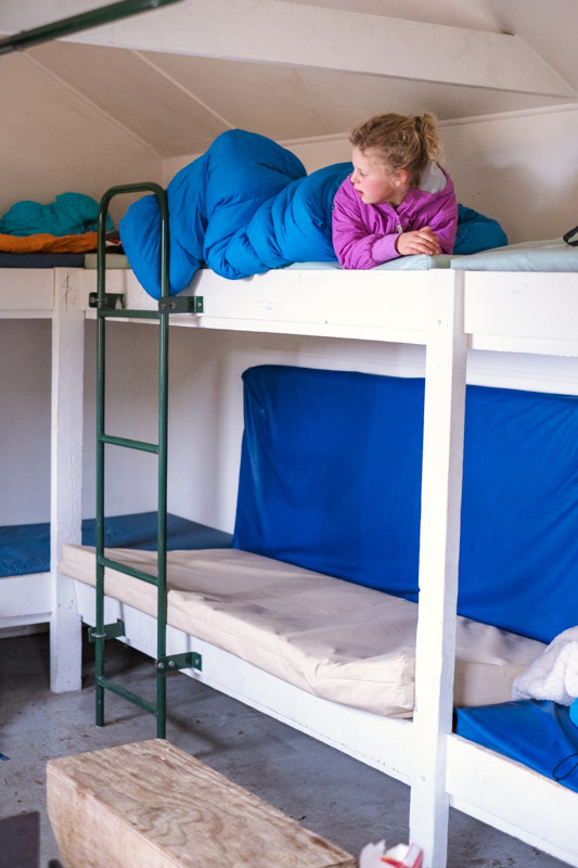 emilia lies in her sleeping bag on the top bunk at Mt fyffe hut in winter