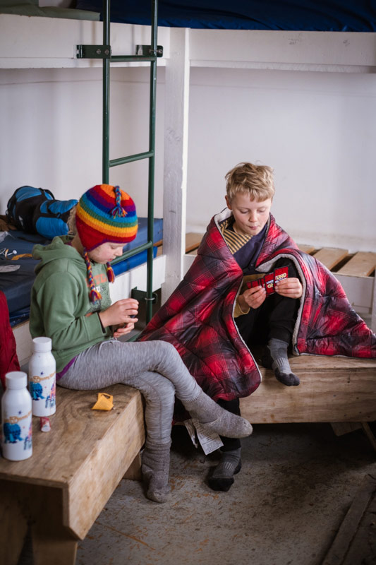 kids sit by the fire playing cards at Mt fyffe Hut kaikoura