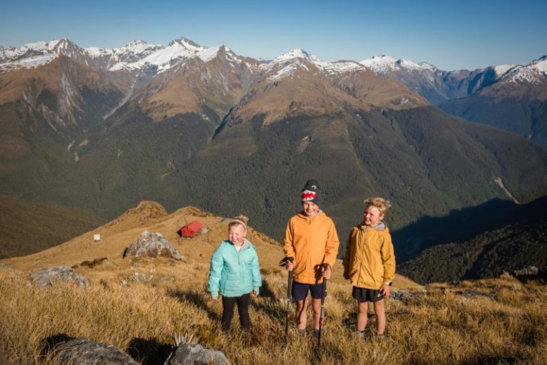 Kids climb up above Brewster Hut on a sunny spring morning