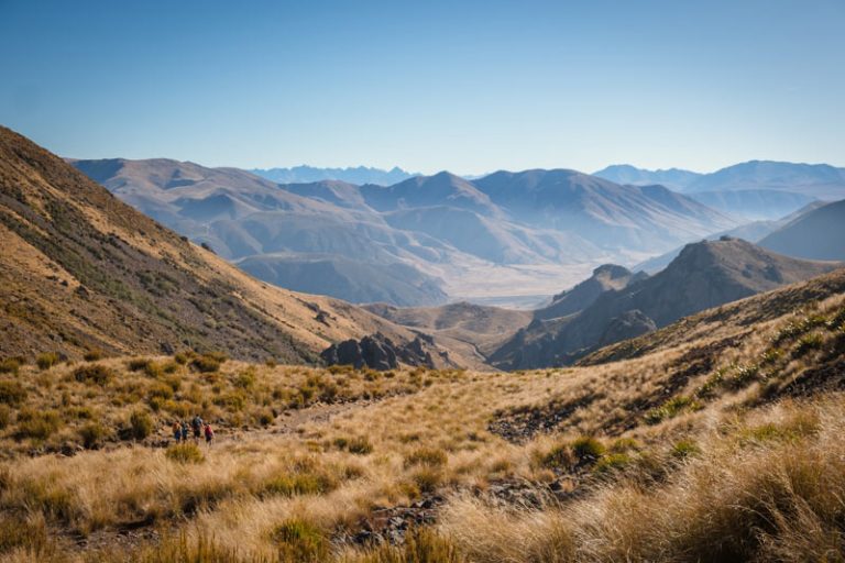 Beautiful golden open expanse of land in the Canterbury High Country with a family looking small, showing perspective on the vastness of the land on the Mt Somers walk