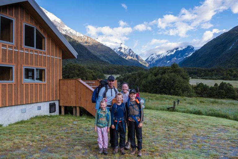 Backyard Travel Family stand in front of family friendly Aspiring Hut in Mt Aspiring National Park