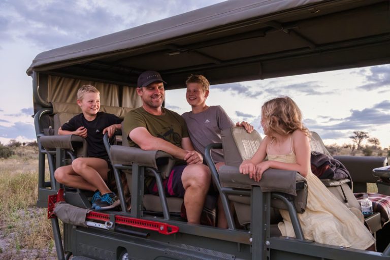 Family sits in a landcruiser on a game drive on safari in Botswana