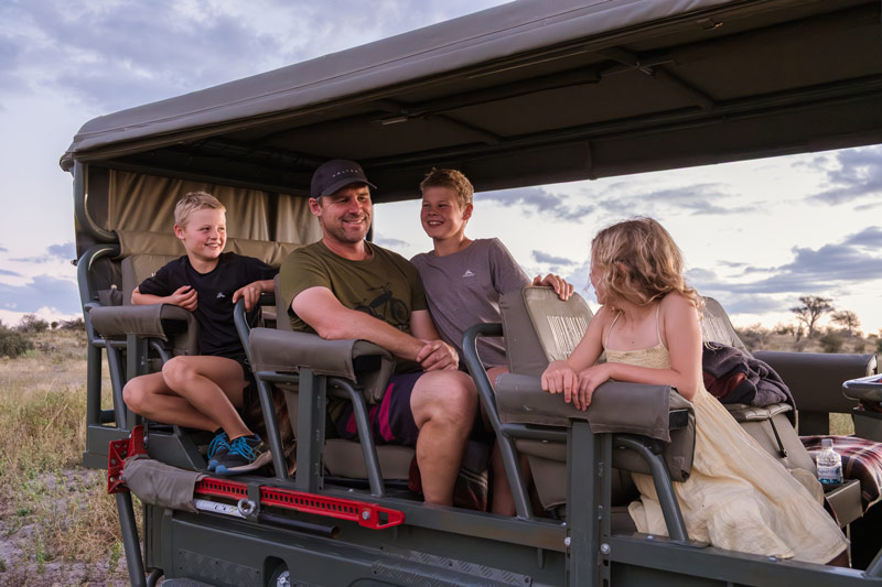 Family sits in a landcruiser on a game drive on safari in Botswana