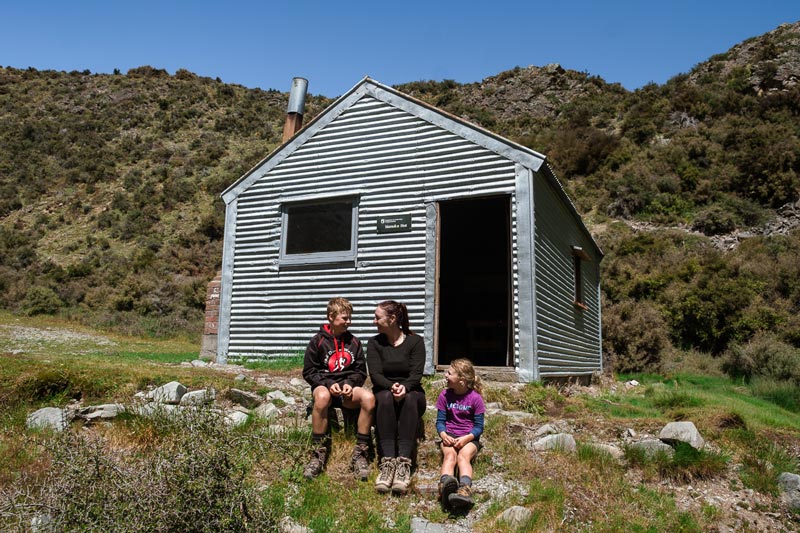 Family sit in front of Manuka Hut